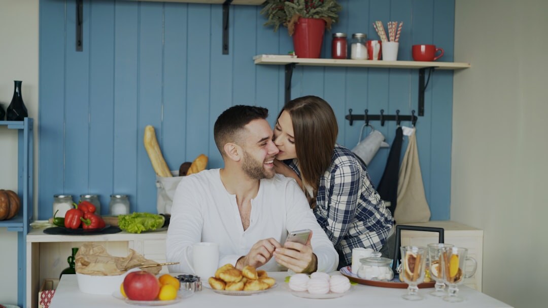 Caucasian couple planning a trip with a paper map and phone at a wooden table